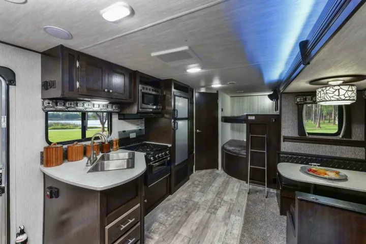 Modern RV rental interior featuring a fully equipped kitchen, dining booth, and convenient bunk beds.. Heartland Pioneer 2016