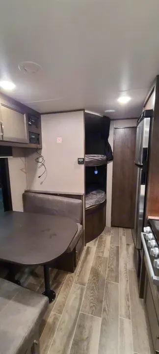 Inside a clean RV rental: a comfortable dinette, two bunk beds with dark curtains, and a kitchen with stainless steel appliances.. Jayco Jay Flight 2021