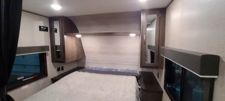 This RV rental bedroom features a cozy bed, built-in storage, and windows, ideal for travel adventures.. Jayco Jay Flight 2021