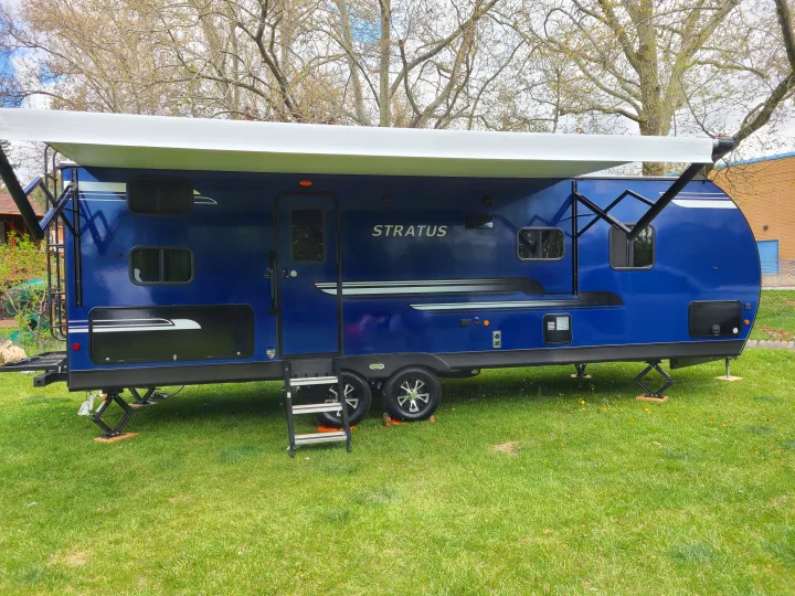 Ready for adventure! Blue Stratus travel trailer RV rental with an extended awning, parked on vibrant green grass.. Venture Rv 261 VBH 2021