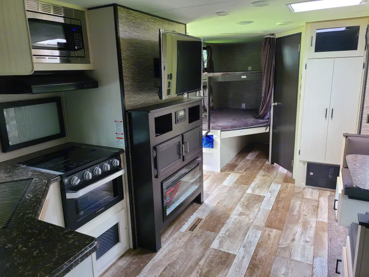 Modern RV rental interior showing a full kitchen, living area with TV and fireplace, bunk beds, and dinette.. Venture Rv 261 VBH 2021
