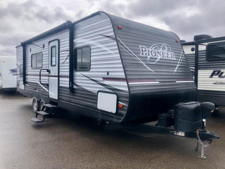Grey Pioneer travel trailer exterior, with an awning & steps, parked on asphalt. Ideal for your next RV rental.. Pioneer Travel Trailer 2018