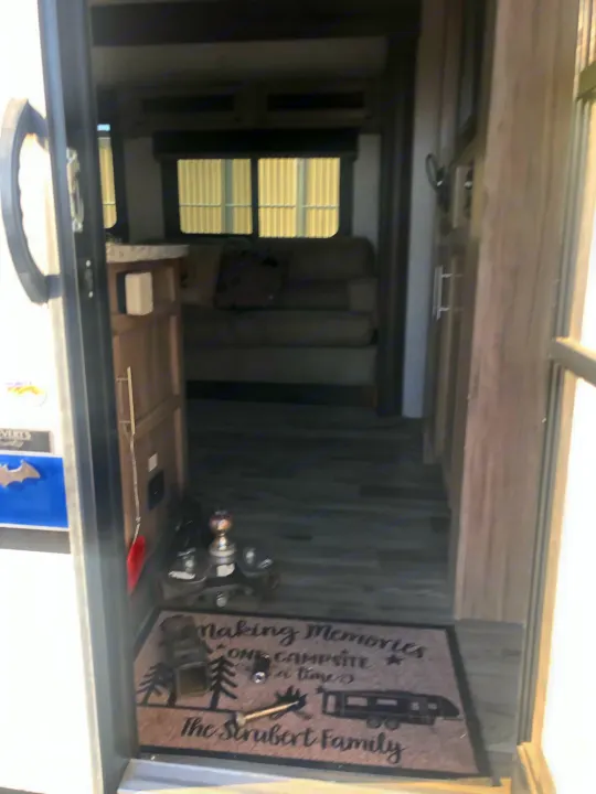 RV rental interior. View of the living space with a sofa, windows, wood-look floor, and a personalized welcome mat at the entrance.. Jayco Jay Feather 2018