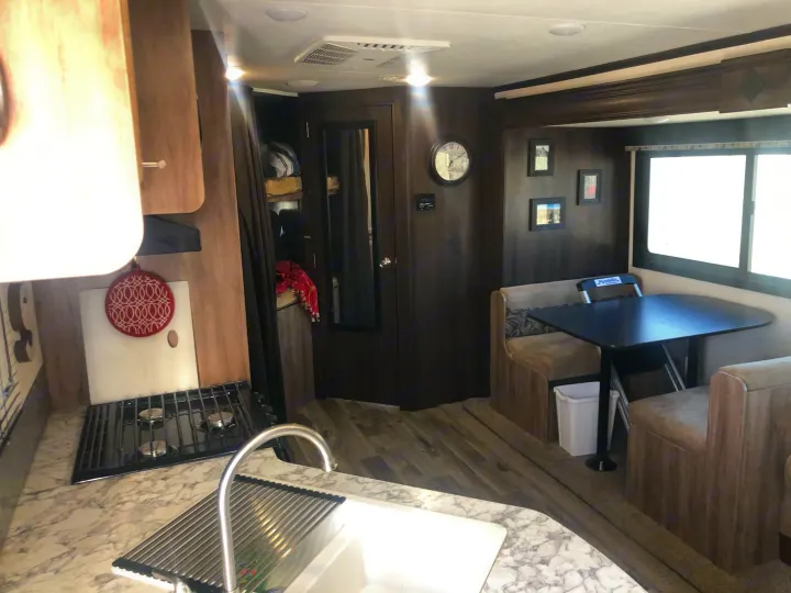 Spacious RV rental interior shows kitchen with stove, sink, and a cozy dinette. Perfect for travel and mobile living.. Jayco Jay Feather 2018
