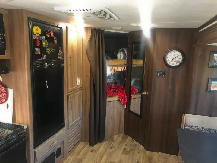 Discover this spacious rv rental interior, featuring a kitchen with a fridge, cozy bunk beds, and a dining area.. Jayco Jay Feather 2018