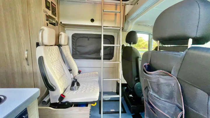 Inside a modern RV rental, showcasing comfortable seating, an overhead bunk ladder, and practical amenities for travel.. Winnebago Solis 2022