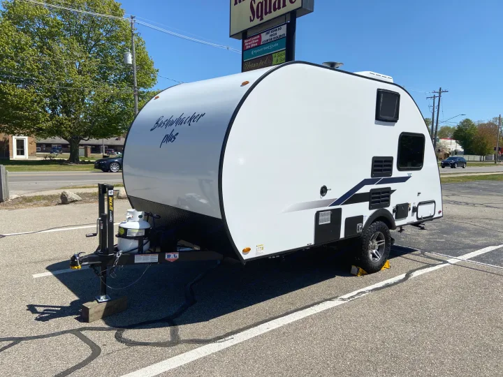 Compact Bushwhacker Plus RV rental, a white teardrop travel trailer, parked in a lot, ready for your next adventure.. Bushwacker 17BH 2021