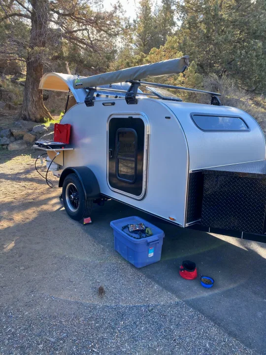 This compact silver teardrop RV rental is set up for outdoor living, featuring a rear kitchen, awning, and convenient pet supplies.. Aero Teardrops Teardrop Camper 2022