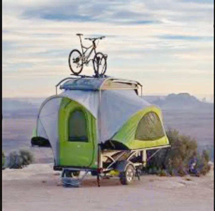 Small green camping trailer with tent & bike, parked in a desert landscape. Perfect RV rental for an outdoor adventure.. Other Other 2018