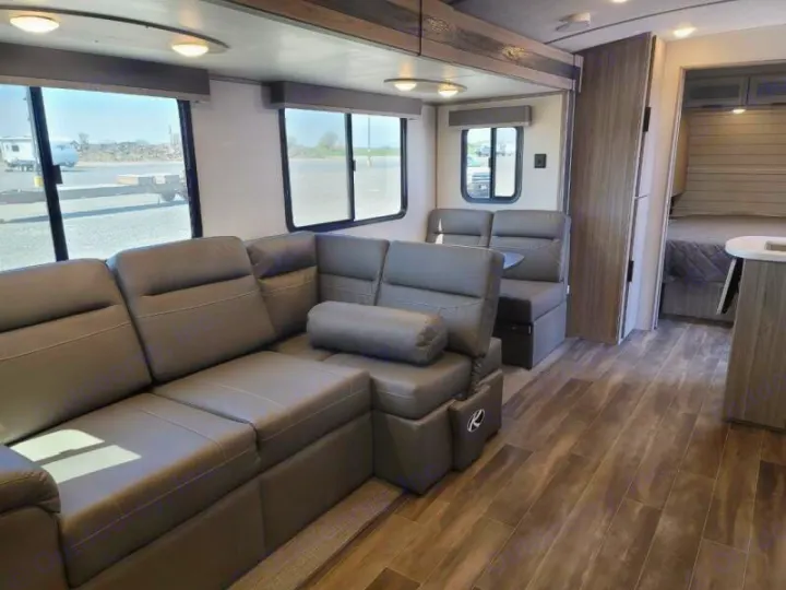 Explore this modern RV rental interior featuring a large sectional sofa, dinette, and private bedroom.. Keystone Passport 2021