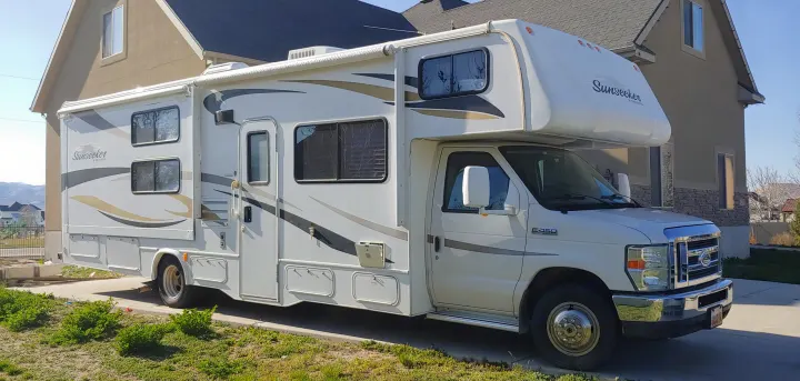 White Sunseeker E-450 Class C RV rental with a slide-out, parked on a driveway, ready for travel.. Forest River Sunseeker 2012