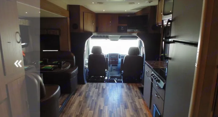 Spacious rv rental interior featuring cockpit, kitchen, and dining area. View from the rear looking forward.. Dynamax Corp Isata 2016