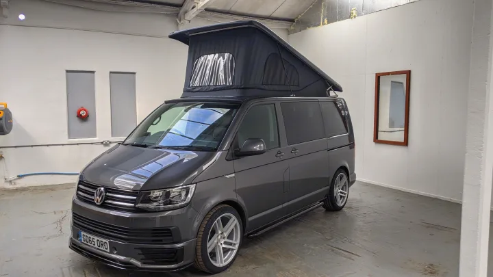 A dark grey VW Transporter camper van with a raised pop-top roof, ideal for an RV rental adventure.. vw T6 2016