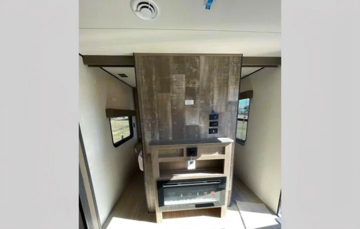 Spacious RV rental interior with a central entertainment unit, electric fireplace, and walkways to other areas.. Other Hideout 2021
