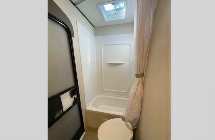 RV rental bathroom interior featuring a compact shower/bathtub, toilet, and ceiling vent for your next adventure.. Other Hideout 2021