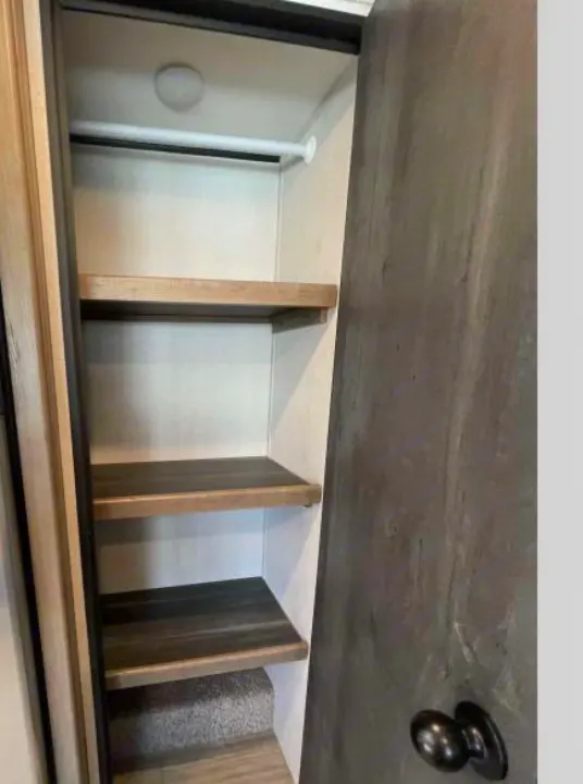 RV rental: Bright interior closet with a hanging rod, multiple wooden shelves, and carpeted floor space.. Other Hideout 2021