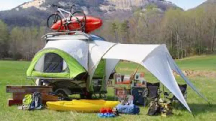 An RV rental teardrop trailer, outfitted with bikes, kayaks, and a tent setup, ready for outdoor camping adventures.. Other Other 2018