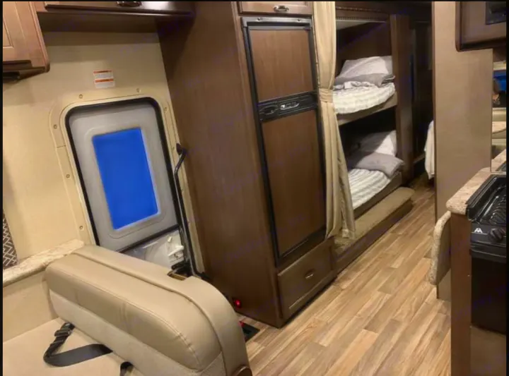 Inside an RV rental: a cozy space with bunk beds, a compact kitchen, and seating near the exit door. Perfect for family adventures.. Thor Motor Coach Four Winds 2019
