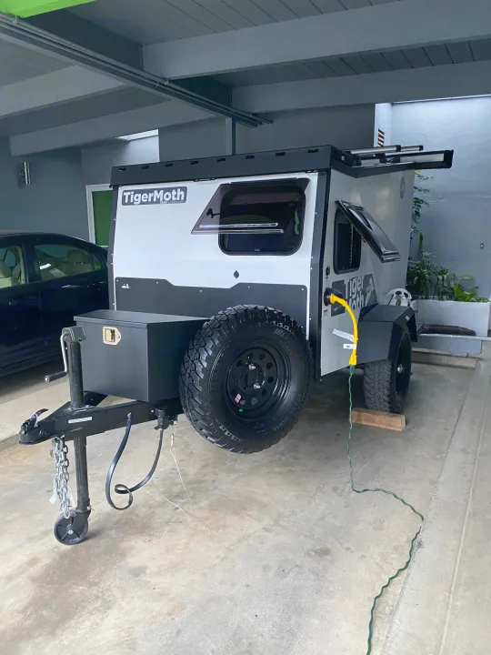 Gray Tigermoth compact off-road trailer with spare tire, hooked up & ready for your next RV rental adventure.. TAXA Outdoors Tigermoth Camper 2021