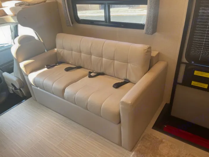 RV rental interior: A beige sofa with seatbelts, typical for a camper or motorhome, showing a comfortable travel space.. Jayco Greyhawk prestige 30XP 2020