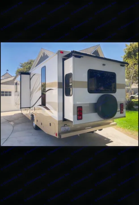 This white and tan RV rental, with slide-outs extended and a spare tire on the rear, is parked in a sunny driveway.. Fleetwood Jamboree Sport 2014