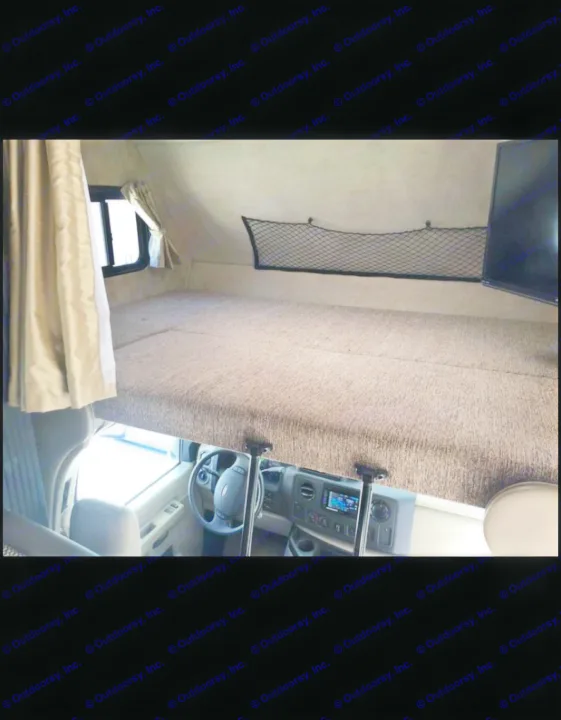 Inside this rv rental: A view of the over-cab bed with window, storage net, and the driver's cockpit below.. Fleetwood Jamboree Sport 2014