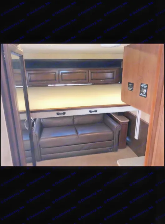 RV rental interior: A compact living space featuring a brown sofa under an overhead bed with dark wood cabinets.. Fleetwood Jamboree Sport 2014