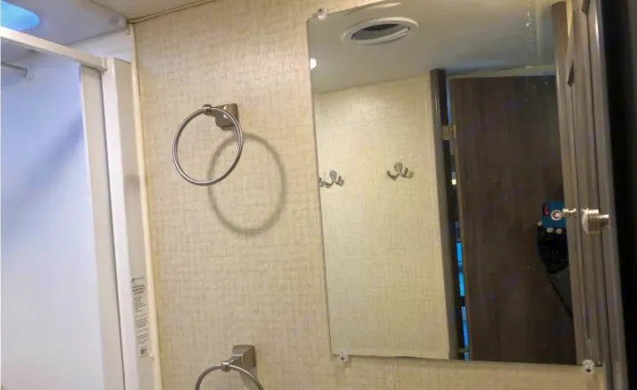 Compact RV rental bathroom with shower, mirror, and towel rings. A door and hooks are reflected in the mirror.. Winnebago Winnebago 2018