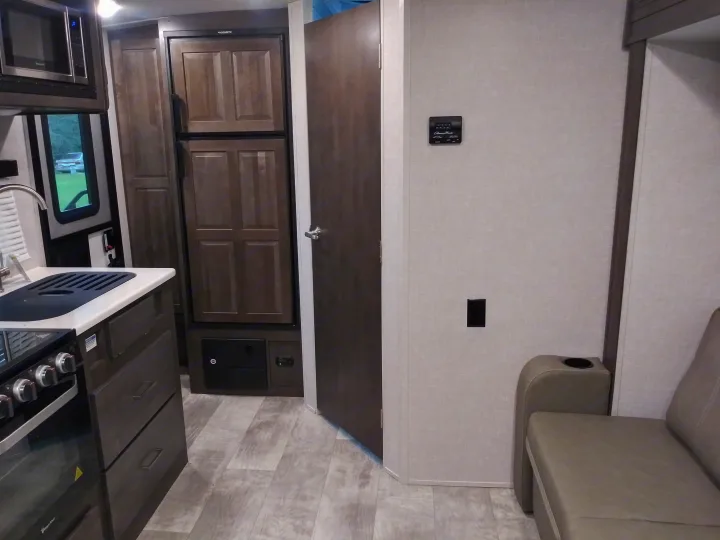 Step inside this RV rental: a compact yet full kitchen with microwave & oven, refrigerator, and comfy sofa.. Forest River Rockwood Mini Lite 2021
