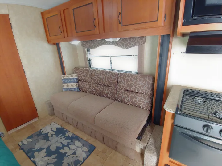 RV rental: Interior view showing living area couch, overhead cabinets, window, and part of kitchen with stove.. Coachmen Catalina 2011