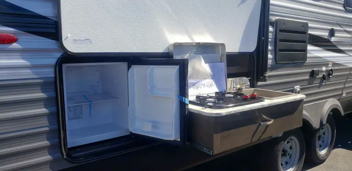 RV rental: Travel trailer outdoor kitchen with open mini-fridge, sink, and two-burner cooktop.. Jayco Jay Flight 2021