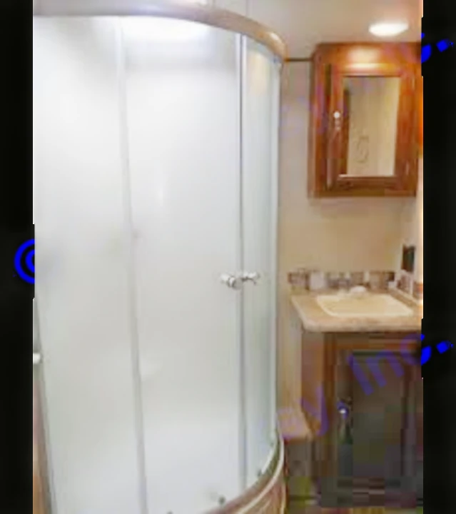 RV rental bathroom with a rounded, frosted glass shower stall and a wood vanity with a sink and mirrored cabinet.. Forest River Vibe 2016