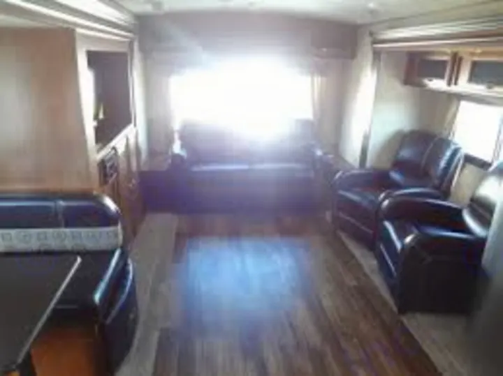 Bright RV rental interior features a spacious living area with dark sofa, recliners, and a dinette. Perfect for travel.. Forest River Vibe 2016