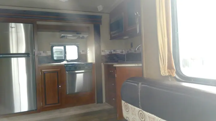 Modern RV rental kitchen interior: stainless steel fridge, stove, microwave, and ample counter space.. Forest River Vibe 2016