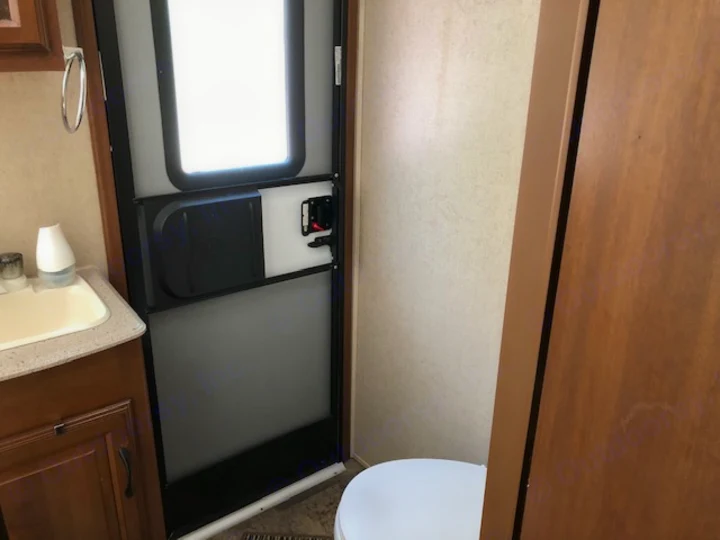 RV rental bathroom interior with sink, door, and toilet visible. Practical space for travel trailer adventures.. Coachmen 310 BHDS 2015
