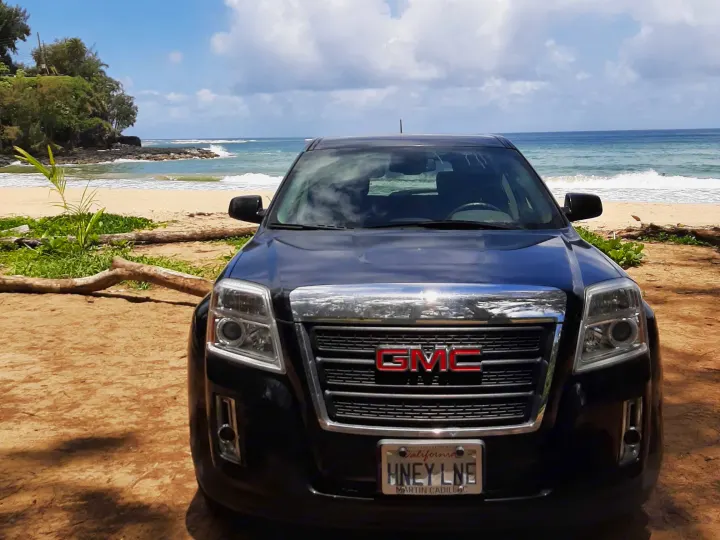 Black GMC SUV parked on a sunny beach with ocean waves. An ideal vehicle for travel. Explore our RV rental options!. Gmc Terrain 2015