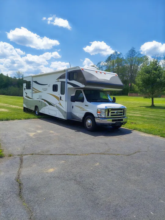 Experience travel freedom in this Winnebago Access RV rental, parked on a sunny day, amidst green landscapes.. Winnebago Access 2011