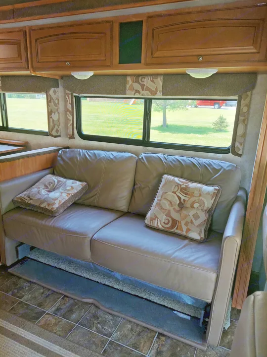 Cozy RV rental interior with comfortable sofa, patterned pillows, and scenic windows. Perfect for your next adventure.. Winnebago Access 2011