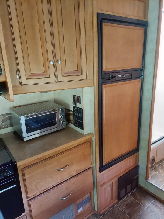 RV rental kitchen: light wood cabinets, Cuisinart toaster oven, and panel-ready refrigerator. RV system controls nearby.. Winnebago Access 2011