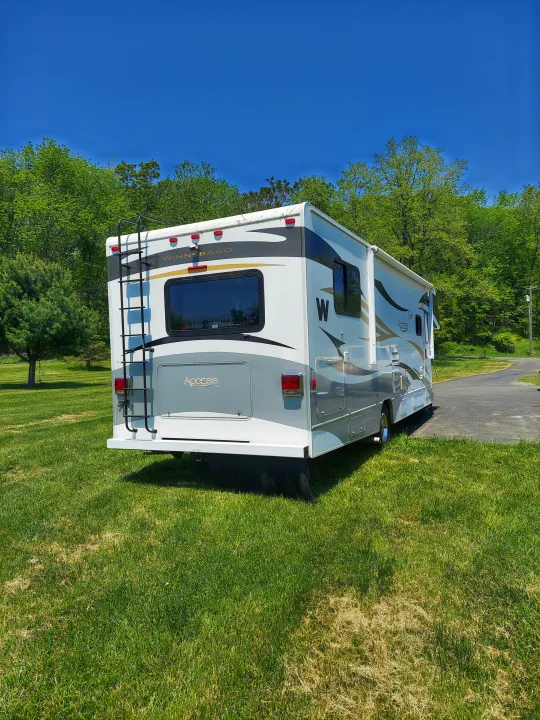 Rear view of a white Winnebago RV parked on green grass. Perfect for an rv rental adventure on a sunny day.. Winnebago Access 2011