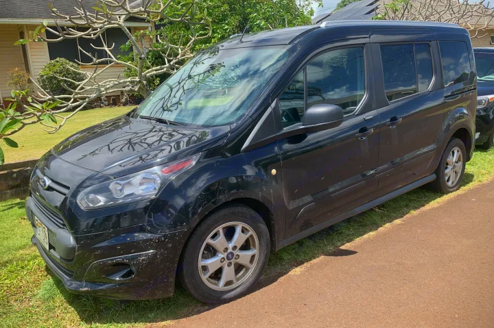 A black Ford Transit Connect van, suitable for a compact RV rental, is parked on grass next to a path.. Other Other 2014