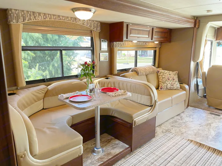 Spacious RV rental interior with U-shaped dinette, inviting dining table, and plush seating, ideal for comfortable travel.. Coachmen Mirada 35BH 2016