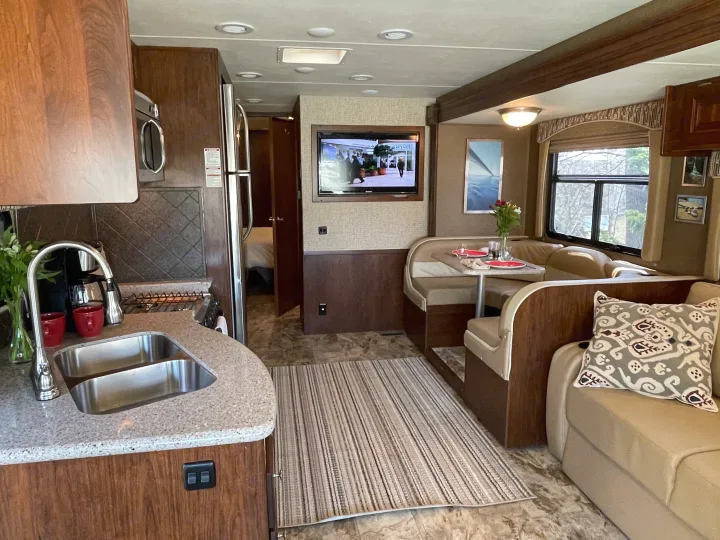 RV rental interior: full kitchen, dining booth, sofa, and TV, offering a comfortable and complete living space.. Coachmen Mirada 35BH 2016