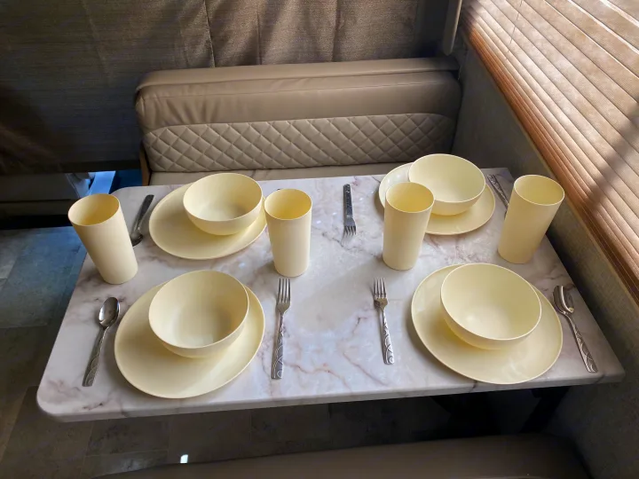 Preparing for meals in your RV rental! This cozy dinette features place settings for four with cream dishes on a marble table.. Gulf Stream Conquest 2019