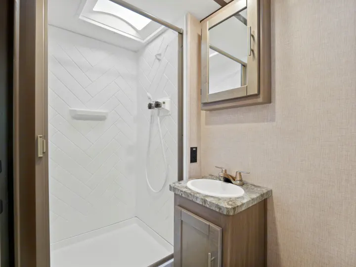 Modern RV rental bathroom with a stylish shower, skylight, vanity, sink, and mirrored cabinet.. Crossroads Sunset Trail Super Lite 2021