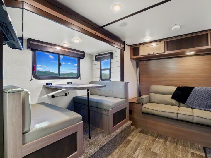 An rv rental's bright interior features a versatile dinette, comfortable sofa, and panoramic window views.. Crossroads Sunset Trail Super Lite 2021