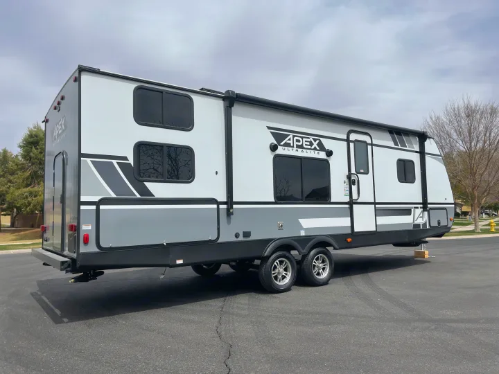 Grey & white Apex Ultralite travel trailer parked on asphalt. Perfect for your next RV rental adventure.. Coachmen Apex 2021