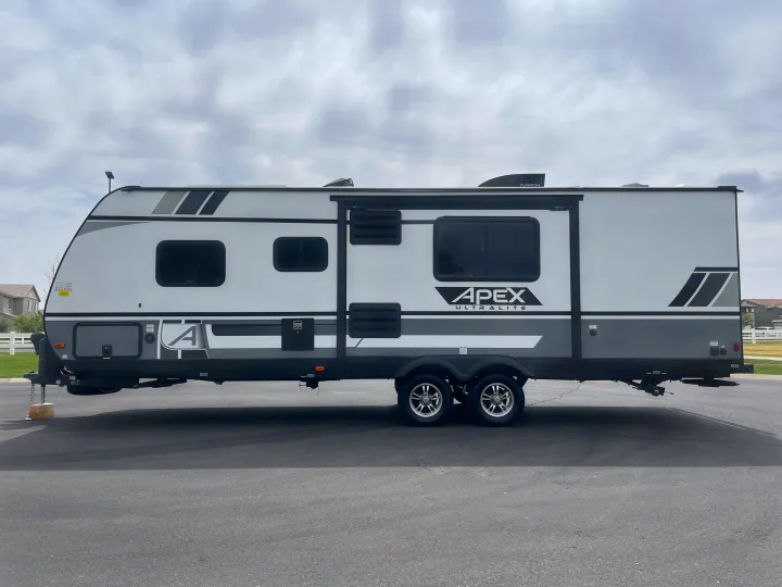 A sleek gray and white Apex Ultralite travel trailer, ideal for an **rv rental** getaway, parked outdoors on asphalt.. Coachmen Apex 2021