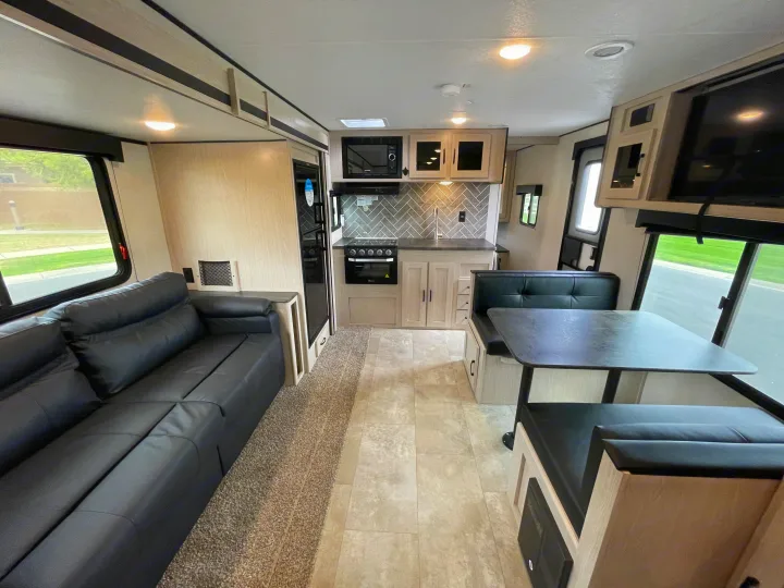 Spacious RV rental interior featuring a modern kitchen, comfortable dinette, and sofa lounge area, ready for travel.. Coachmen Apex 2021