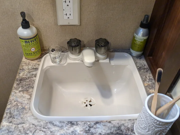 Compact RV rental bathroom with sink, Mrs. Meyer's hand soap, and toothbrushes, showcasing a tidy and practical space.. Other Other 2017